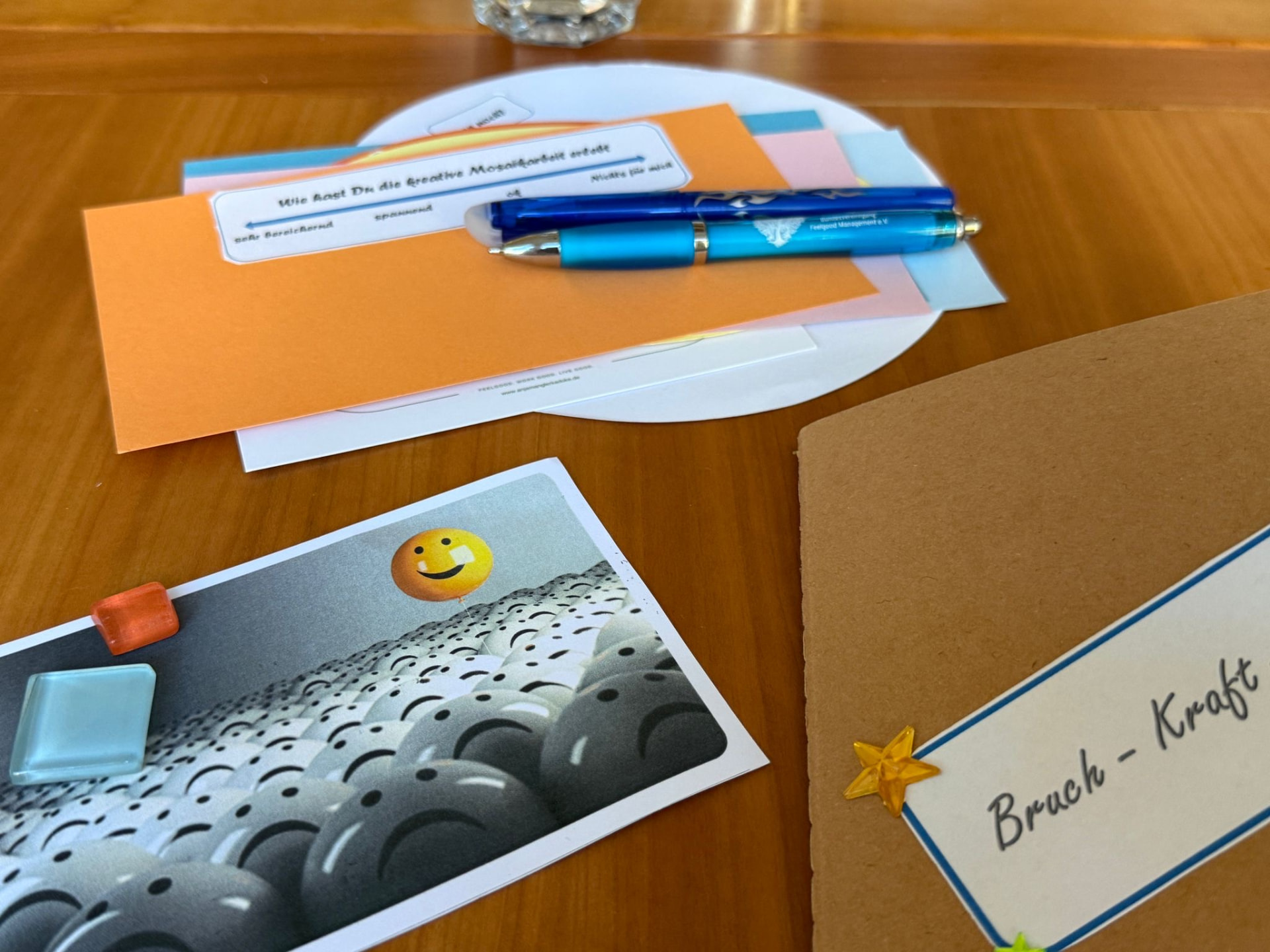 Workshop-Materialien für den Resilienz-Mosaik-Workshop: Reflexionskarten, Mosaiksteine und eine Karte mit der Aufschrift Bruch – Kraft.